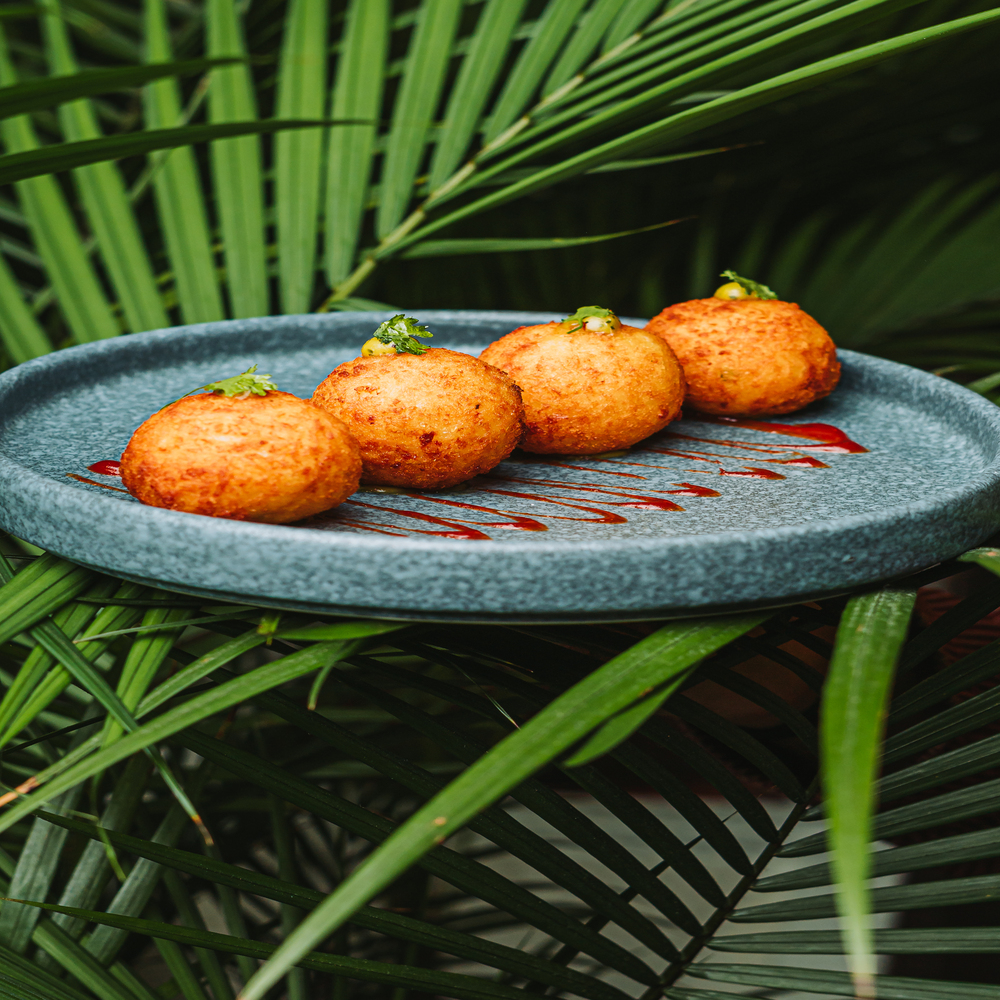 Croquetas de queso servidas entre hojas de palma