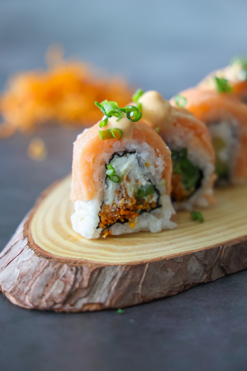 Rollos de salmón con cebollín sobre una tabla de madera