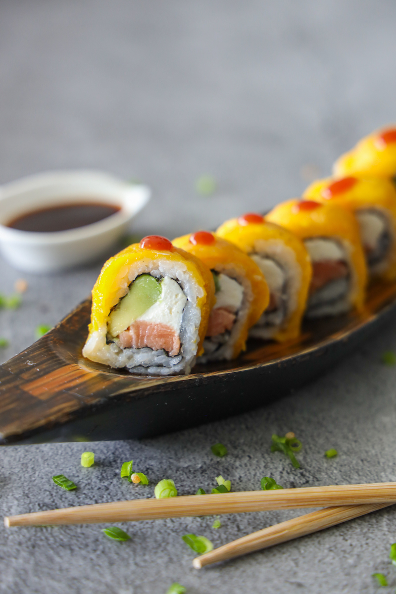 Rollo de sushi cubierto de mango con salsa de soya