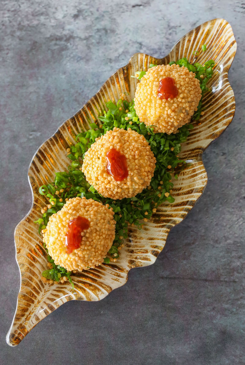 Bolitas empanizadas con salsa picante sobre hojas verdes