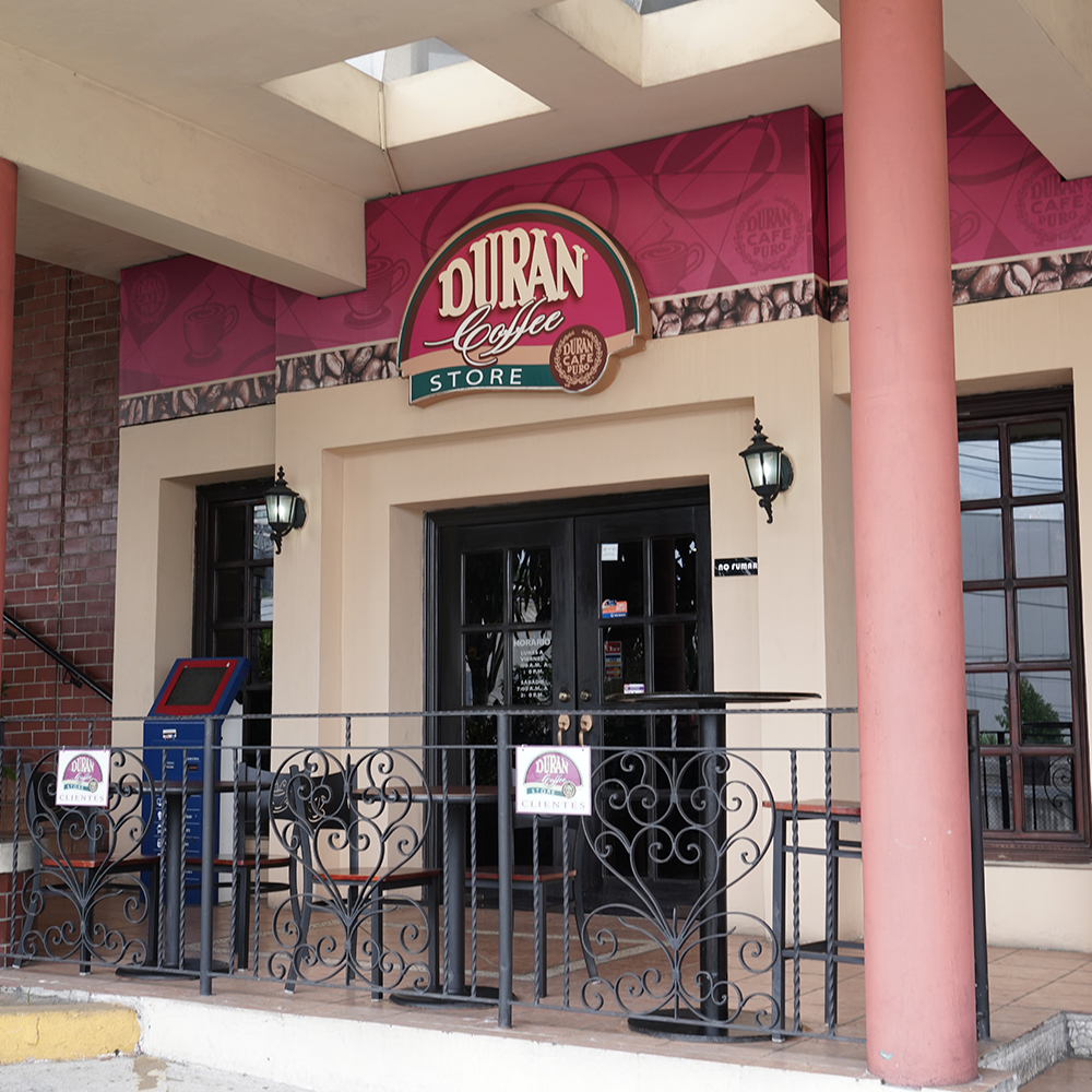 Fachada colonial de un Durán Coffee Store con letrero Durán y balcón de hierro forjado