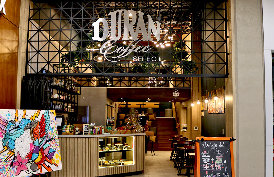 Entrada de Durán Coffee Select con letrero iluminado y estructura metálica