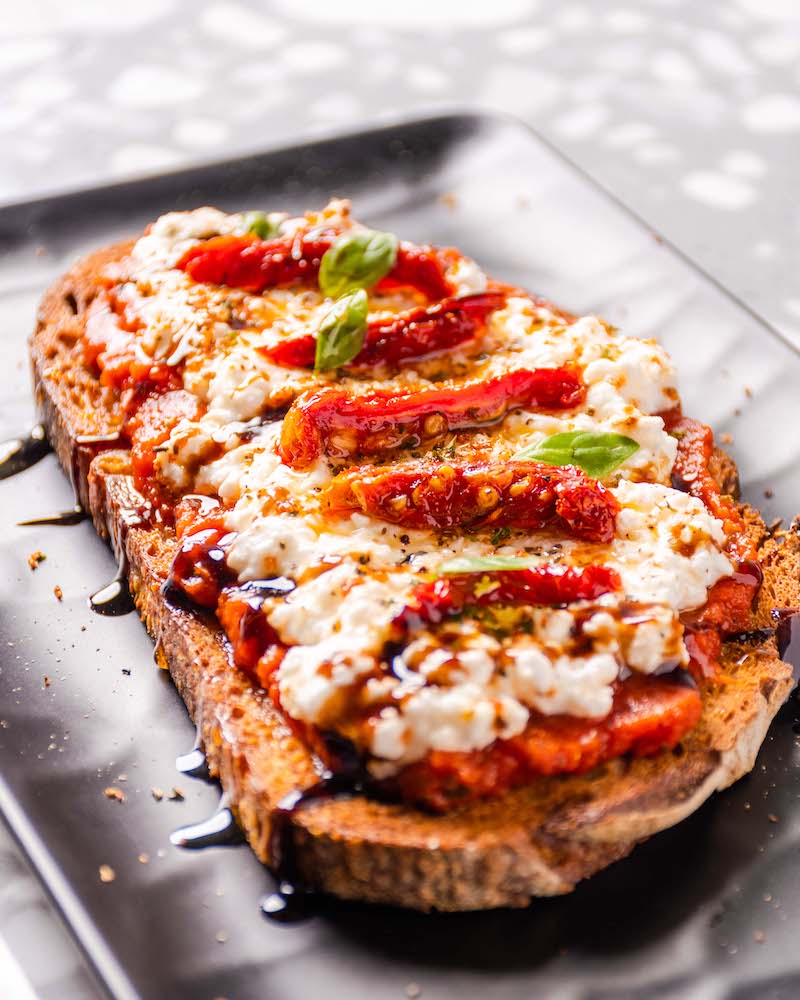 Tostada de pan rústico con salsa de tomate, queso y tomates secos