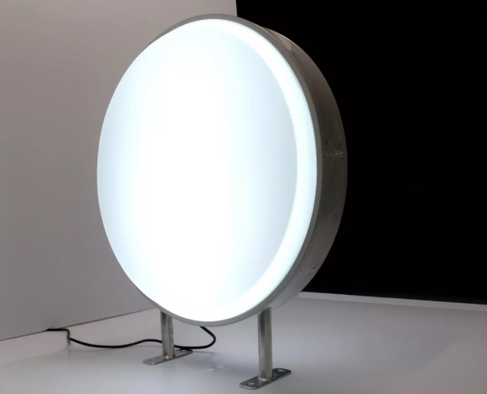 Caja de luz redonda encendida sobre base metálica