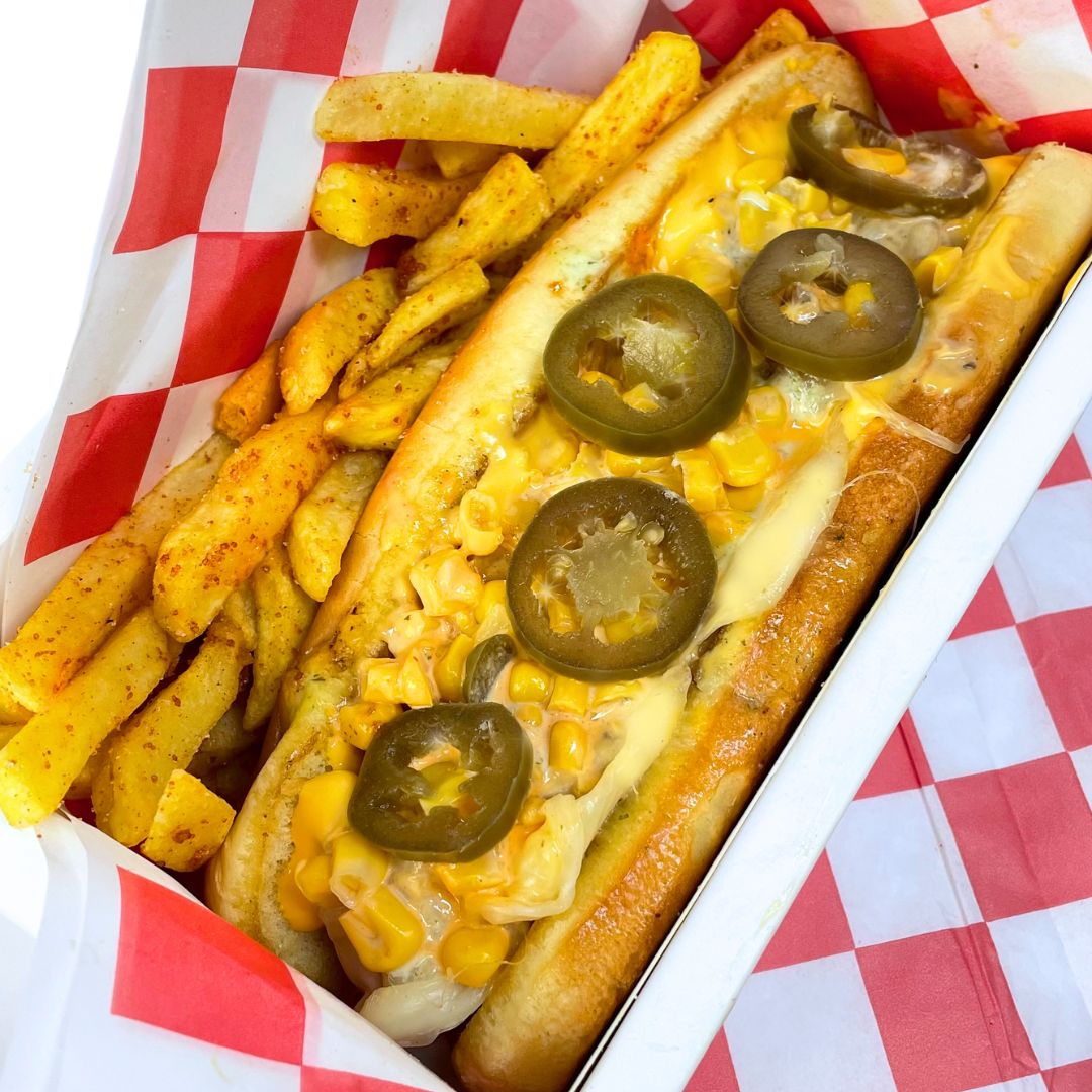 Hot dog con maíz, queso y jalapeños sobre papel a cuadros