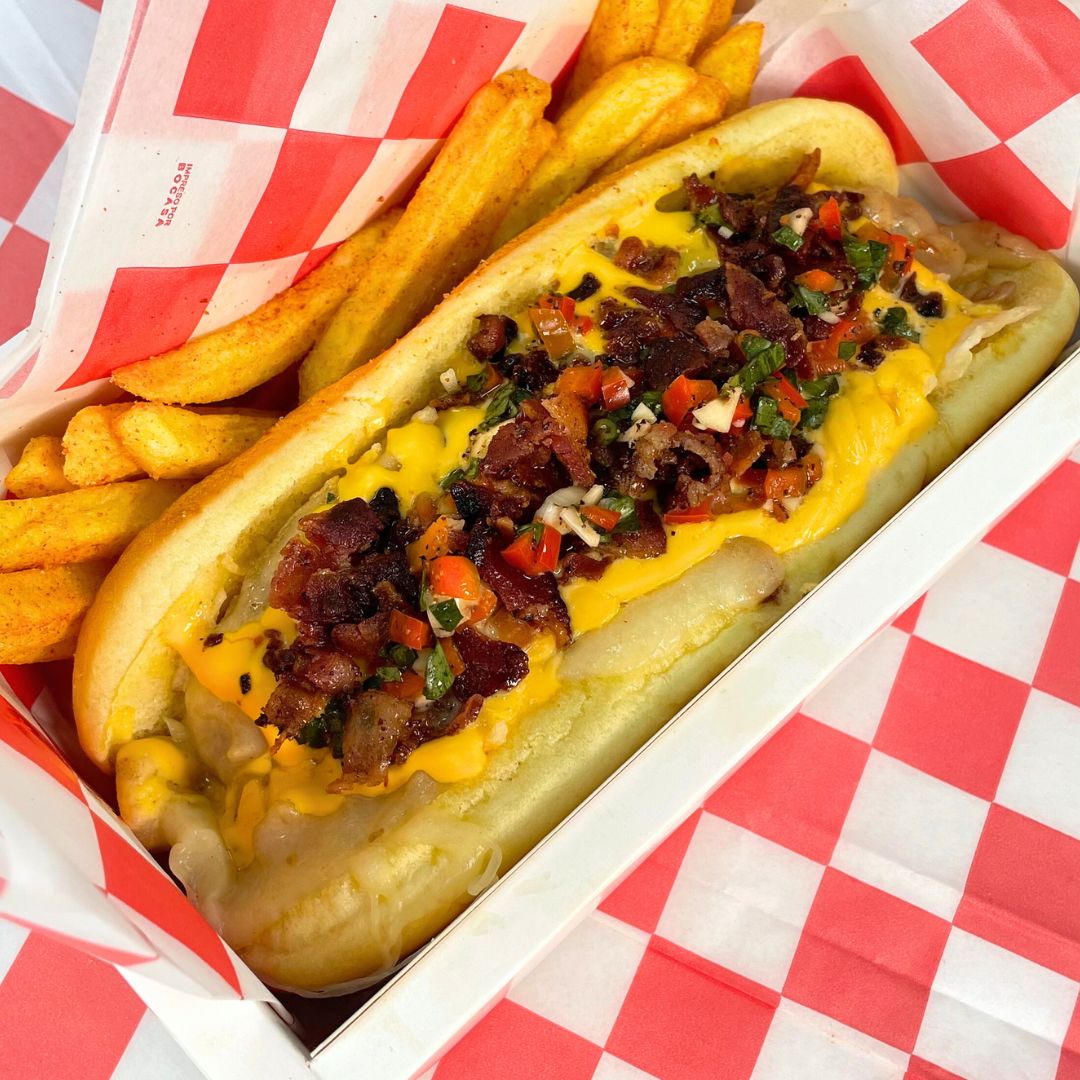 Hot dog con queso, tocino y pico de gallo junto a papas fritas