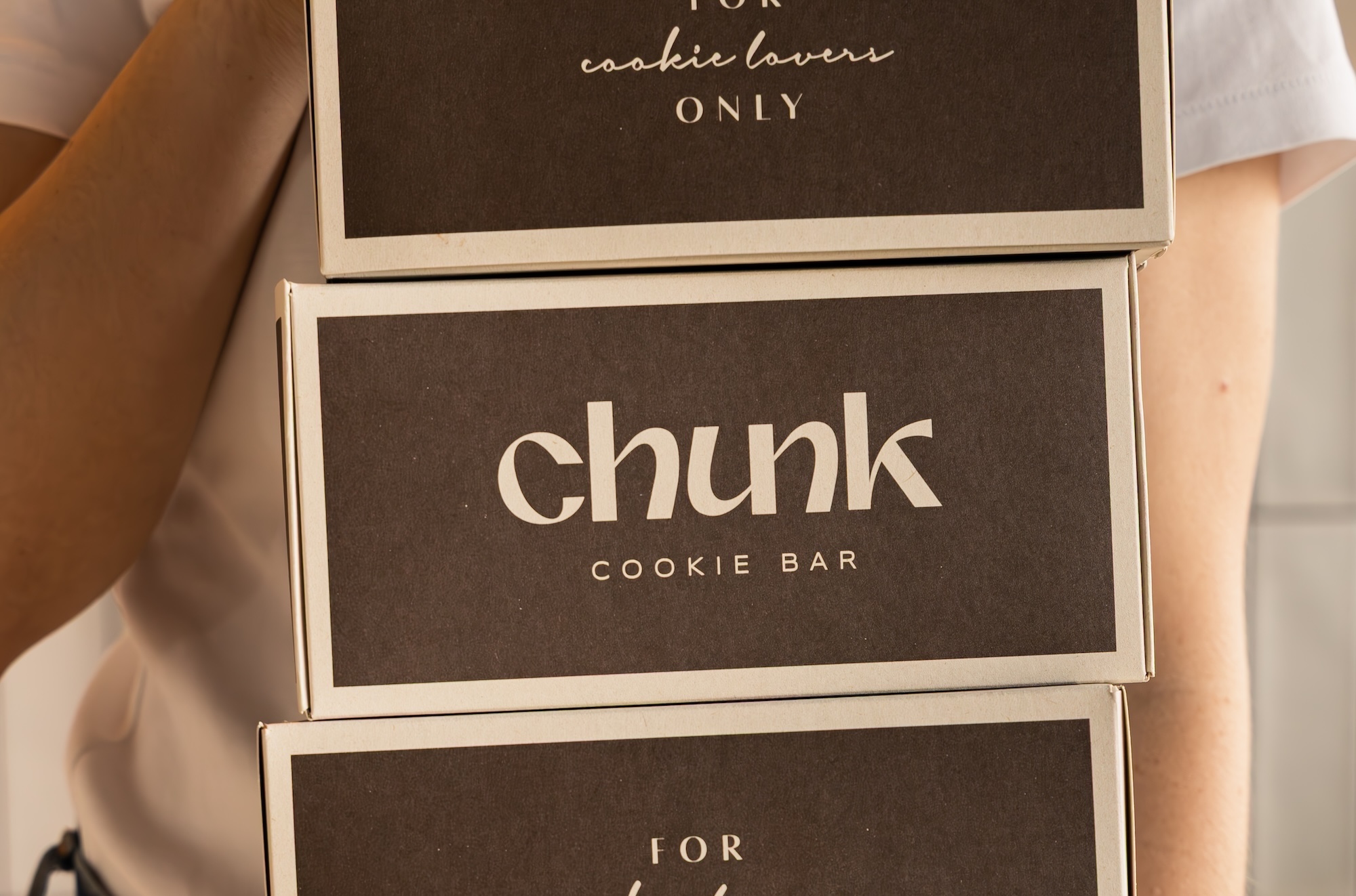 Persona cargando cajas de Chunk cookie bar con el lema For cookie lovers only
