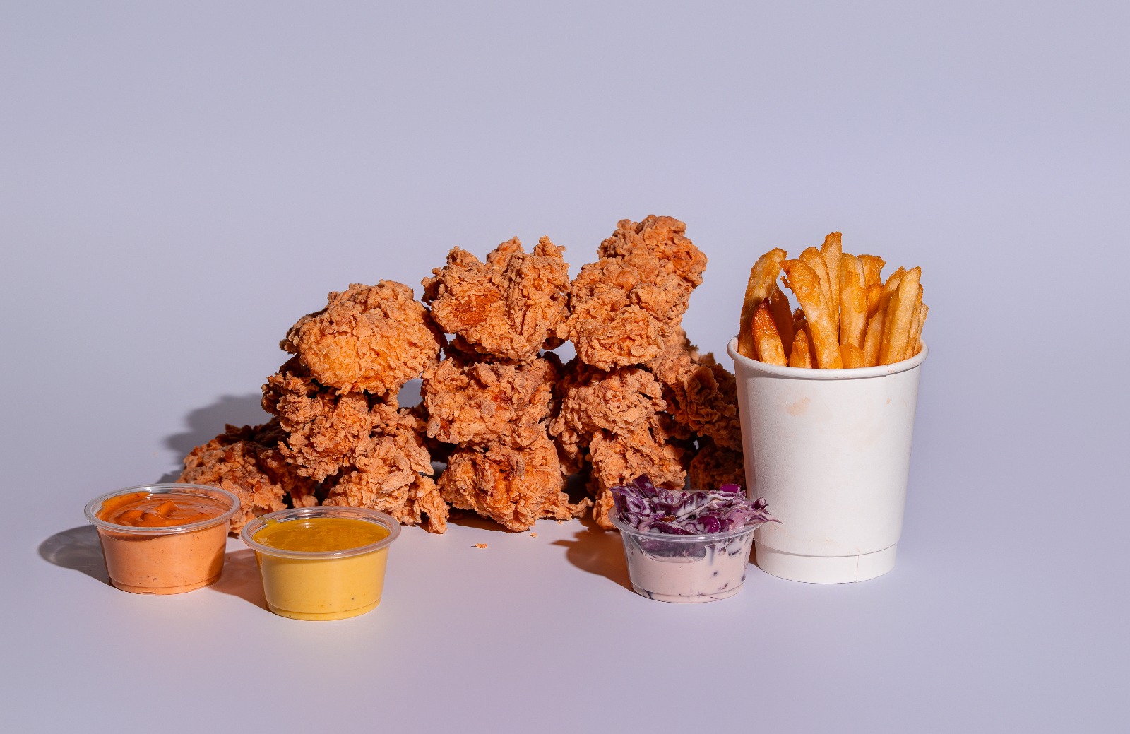 Chicken tenders crujientes de Naked Lukas con fries y tres salsas para mojar