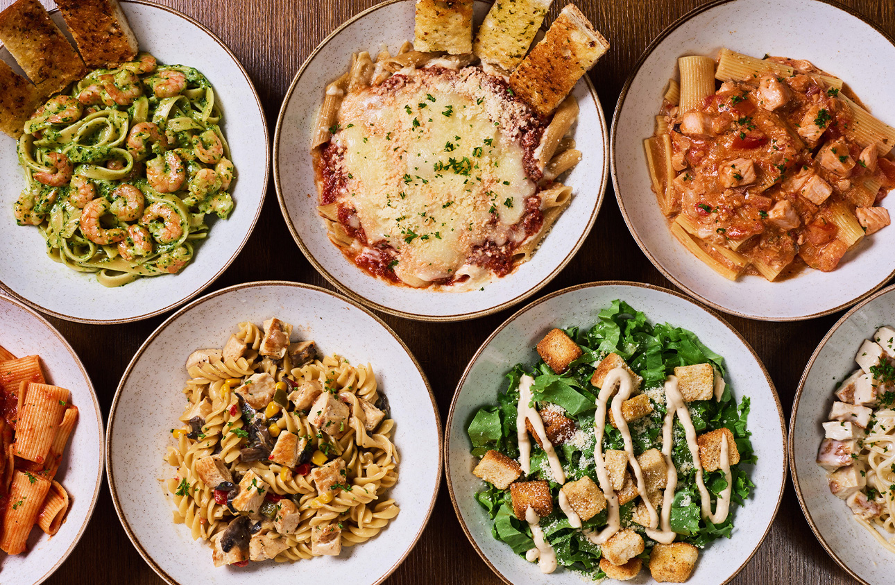 Mesa con platos de pasta, lasaña y ensalada césar