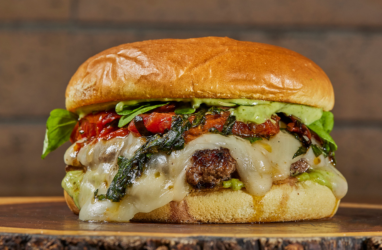Hamburguesa con queso derretido, tomate y hojas verdes
