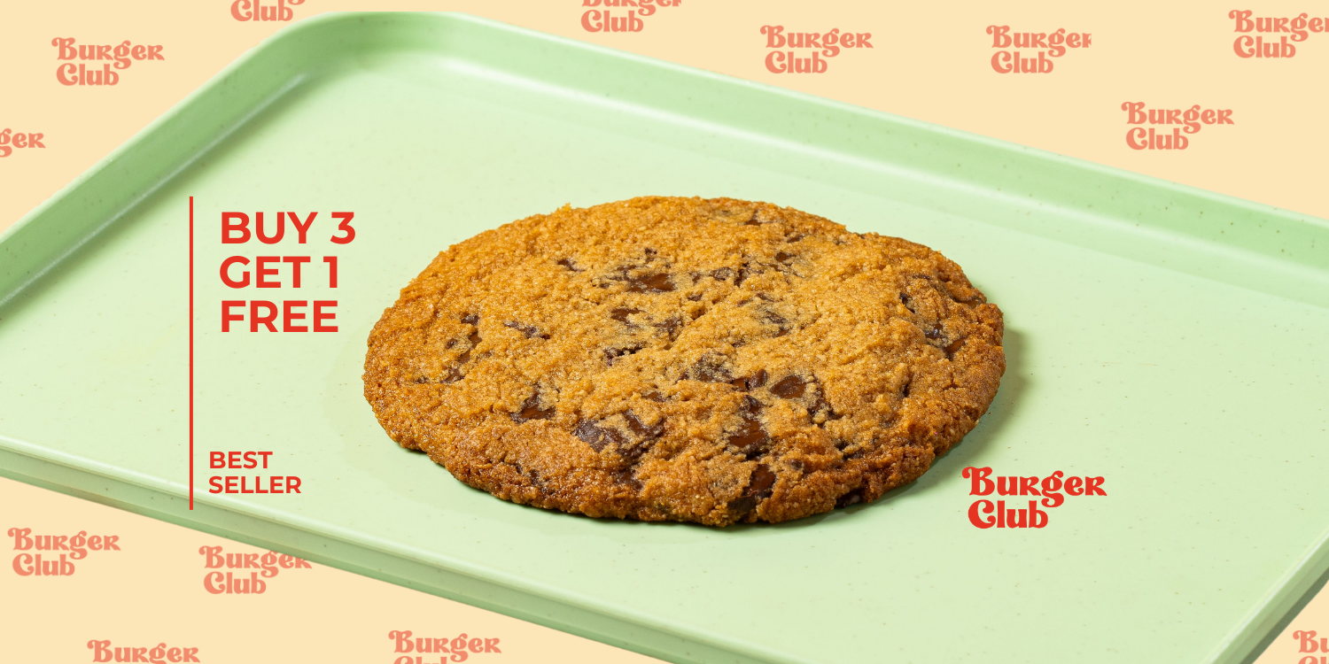 Galleta grande con chispas de chocolate de Burger Club sobre una bandeja verde menta y papel con el logo de la marca