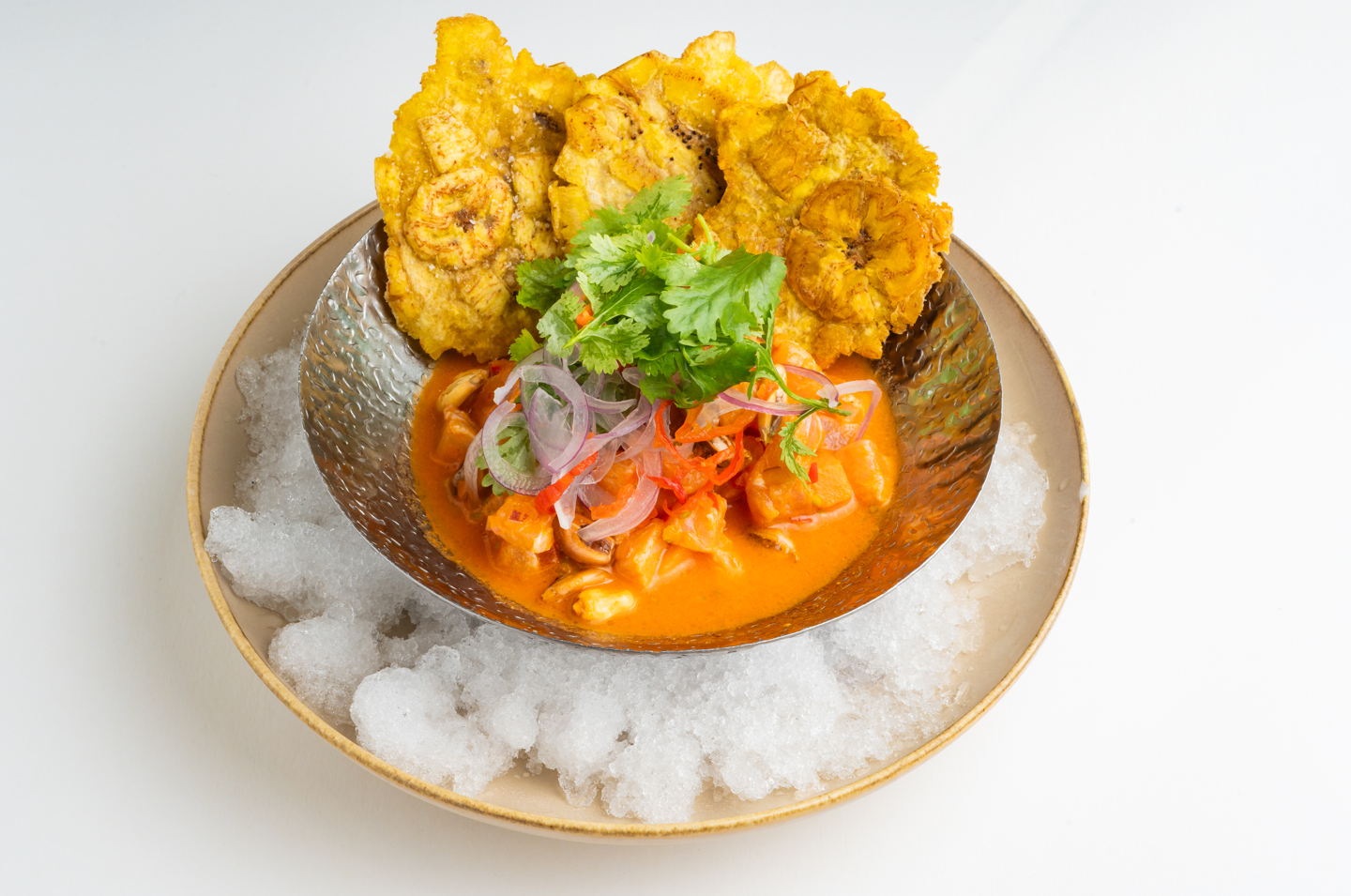 Ceviche en salsa servido sobre hielo con patacones