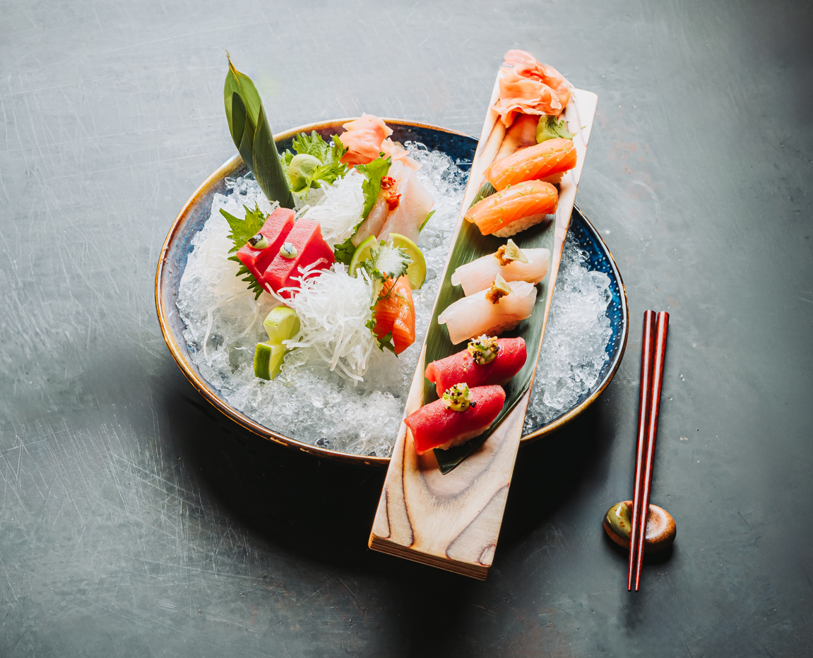 Sashimi y nigiris sobre hielo con palillos en tabla de madera
