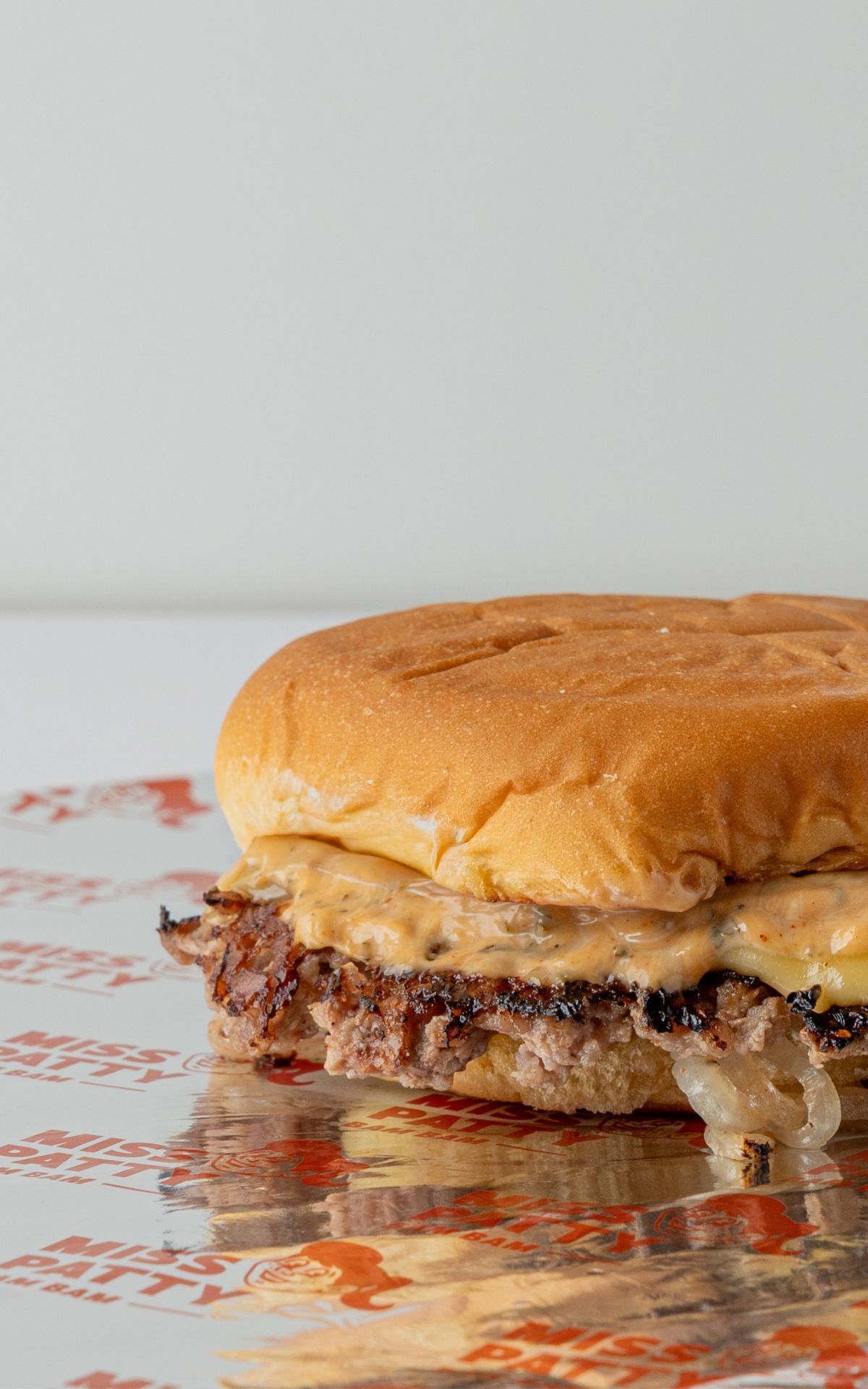 Smash burger de Miss Patty Bam Bam con queso derretido y pan brioche sobre papel de la marca