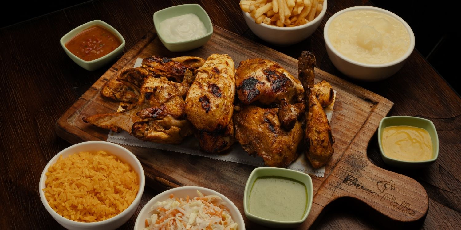 Tabla familiar con pollo asado, papas fritas, arroz amarillo, coleslaw y cinco salsas