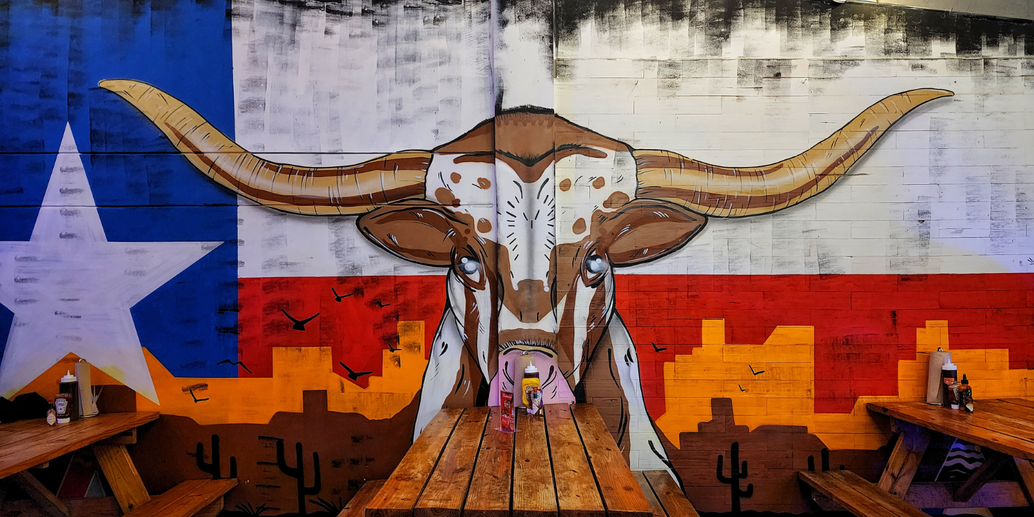 Mural de un toro longhorn sobre la bandera de Texas en el comedor