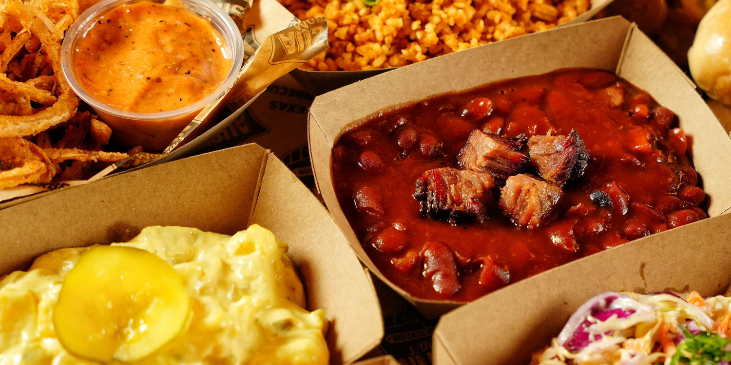 Sides de Austin Mama's en cajas de cartón: frijoles con trozos de brisket, ensalada de papa, arroz y salsa