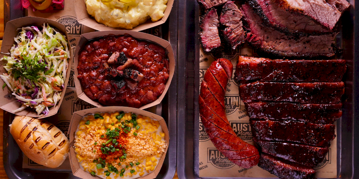 Bandeja de barbecue con brisket en tajadas, salchicha ahumada, coleslaw, frijoles con brisket, mac and cheese, maíz y pan