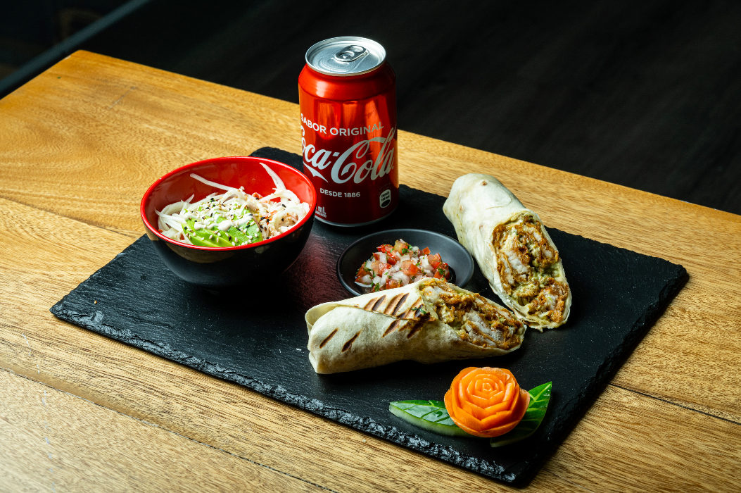 Wraps a la plancha con salsa, ensalada y una lata de Coca-Cola sobre una bandeja de pizarra