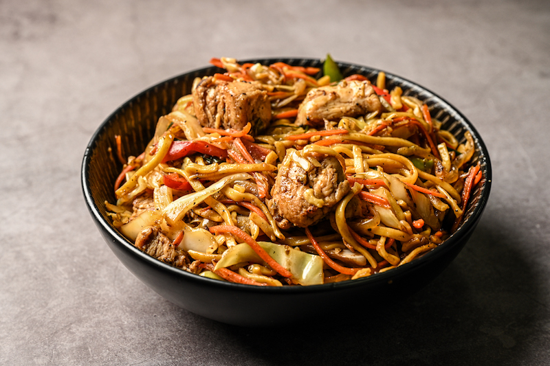 Bowl negro de noodles salteados al wok con pollo y vegetales de Muzka