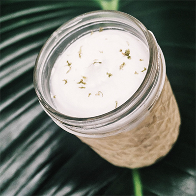 Bebida cremosa servida en frasco de vidrio sobre hoja tropical